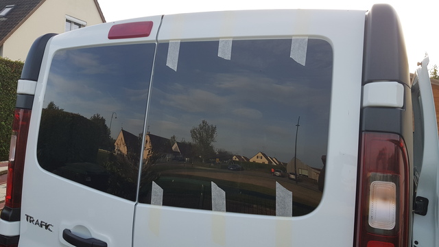 Porte arrière d'un Renault trafic L2H1 dont les parties hautes ont été découpées et mise en place de baies fixes teintées.