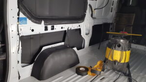 Intérieur d'un Renault trafic L2H1 en cours d'isolation sur les parois métalliques et passage de roue. La photo représente le projet d'aménagement d'un véhicule utilitaire.