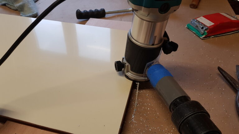 Une défonceuse est utilisée pour affleurer les bords de pièces de bois revêtues de stratifié couleur ivoire.