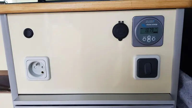 Panneau de contrôle pour van aménagé avec diverses connexions d’alimentation et compteur numérique.