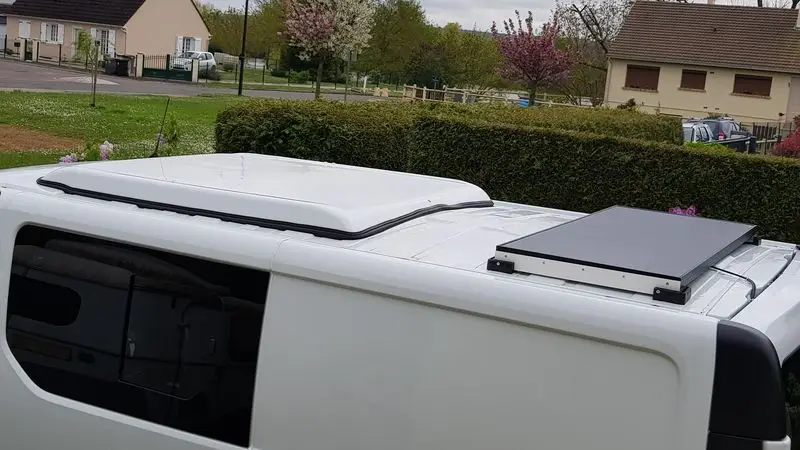 Un Renault trafic L2H1 avec un un toit relevable et un panneau solaire installé à côté.